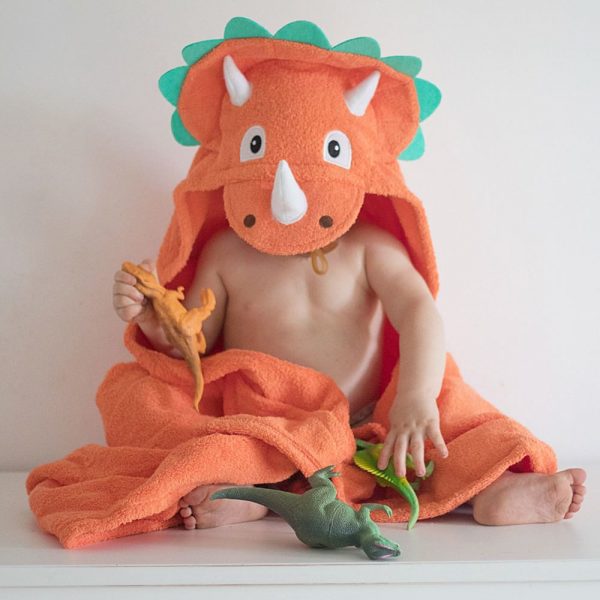 A toddler enjoying play time in their triceratops dinosuar hooded towel by Yikes Twins