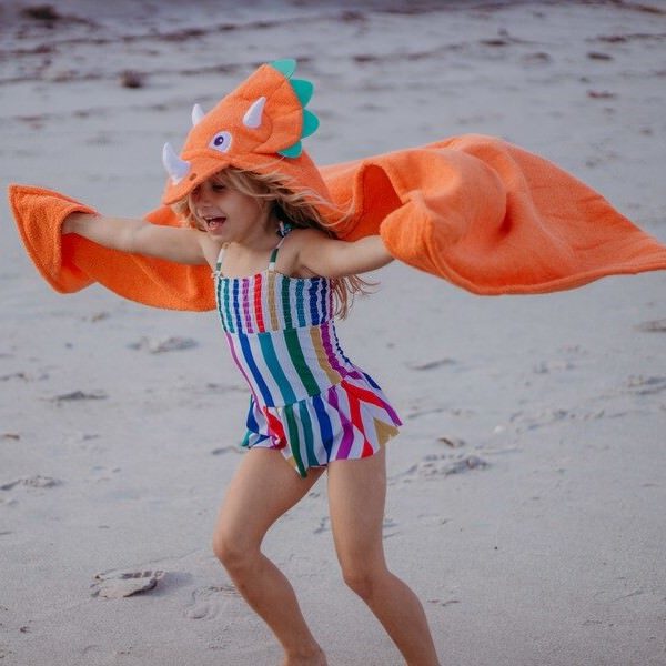 The Yikes Twins dinosaur hooded towel brings much fun to a toddler at the beach
